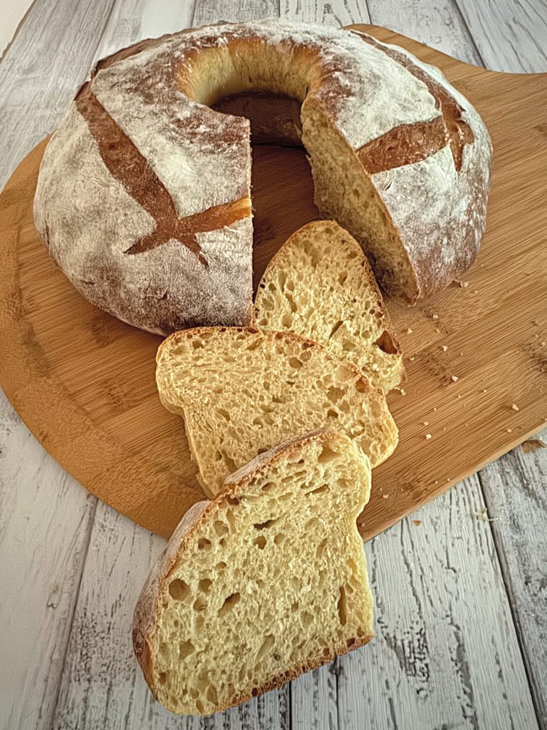 Rustic olive oil brioche ring with a wedge cut out and three slices showing a soft, open golden crumb.