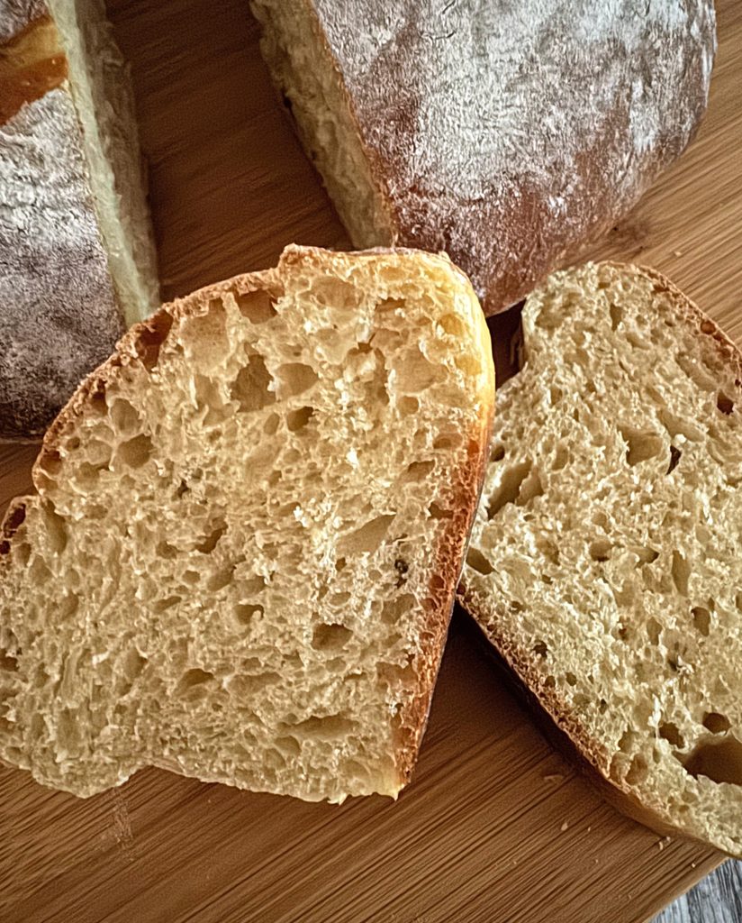 Close-up of two slices of olive oil brioche with an open, airy golden crumb and thin brown crust.