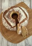 Floured pompe à l’huile ring with four crossed slashes on a wooden board, two slices cut to show the crumb.