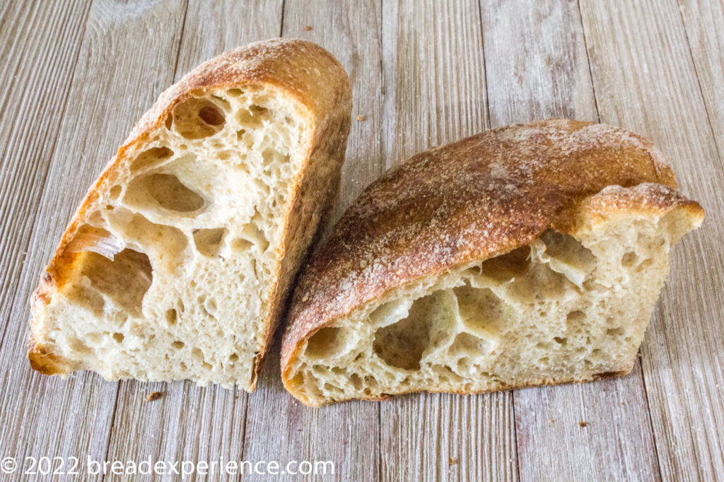 Crumb shot of first bake Pan Gallego cut in half, revealing an open, airy crumb with large irregular holes.