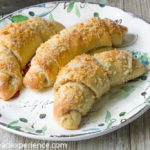Three sugar-coated Spanish bread rolls served on a vintage floral plate atop wood planks.