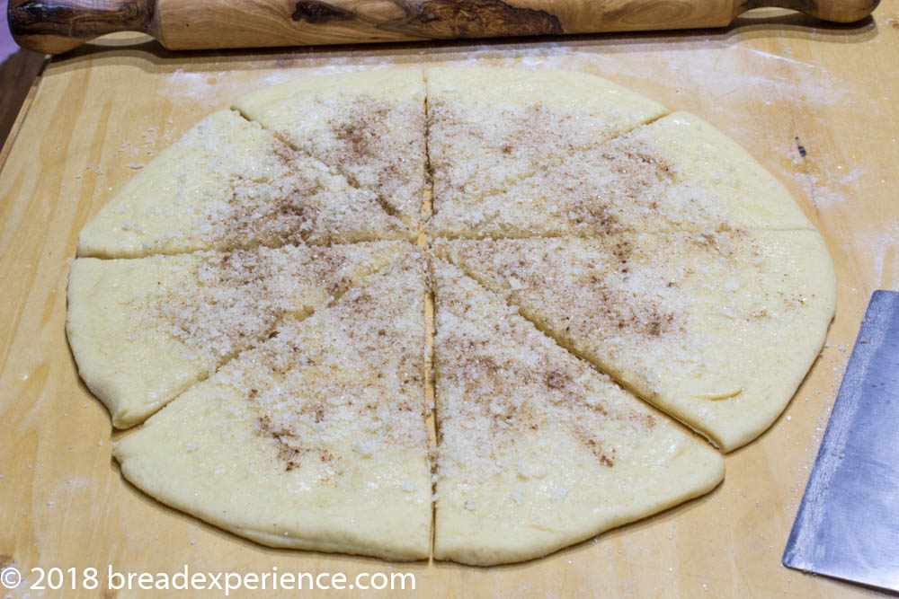 Round of dough topped with cinnamon-sugar filling and scored into eight triangular wedges.