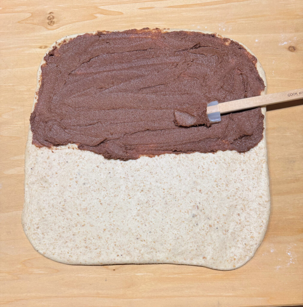 Cinnamon filling spread over the top half of the rolled dough with a small offset spatula.