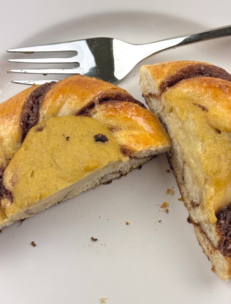 Sourdough Solskinnsboller cut in half, showing the vanilla custard center and cinnamon swirl inside a soft crumb.