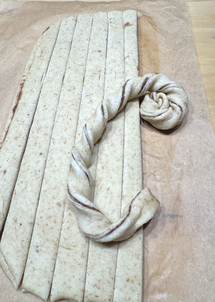 A twisted rope being wound into a coil beside the remaining cut strips.