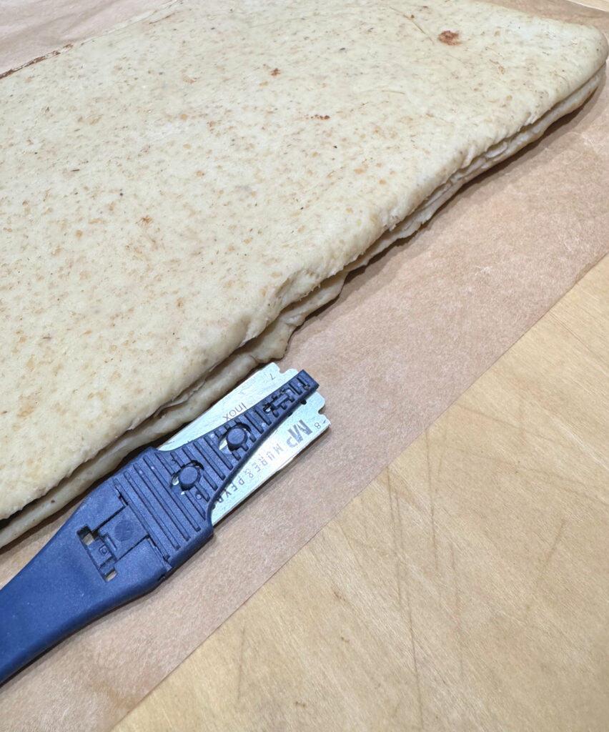 A lame scoring along the folded edge of the chilled dough to open the seam.