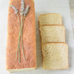 Bee Keeper's Pain de Mie with lavender sprigs, beside three slices showing a soft, tender crumb.
