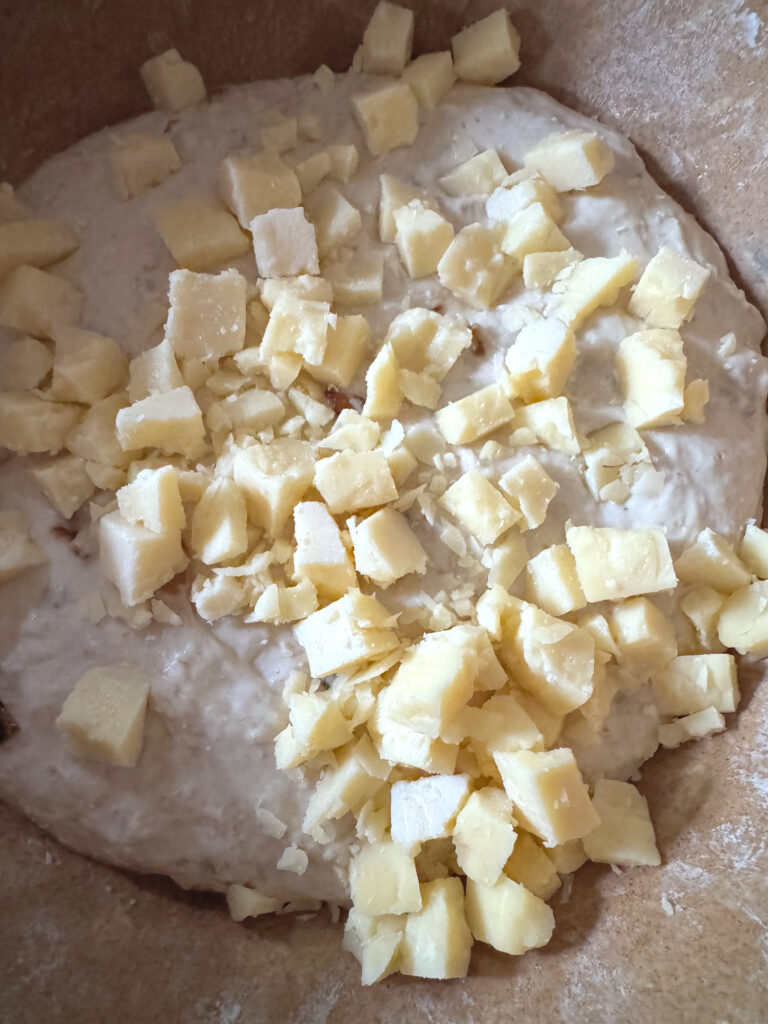 Cubed cheese on top of Caramelized Onion & Gruyère Baguette dough
