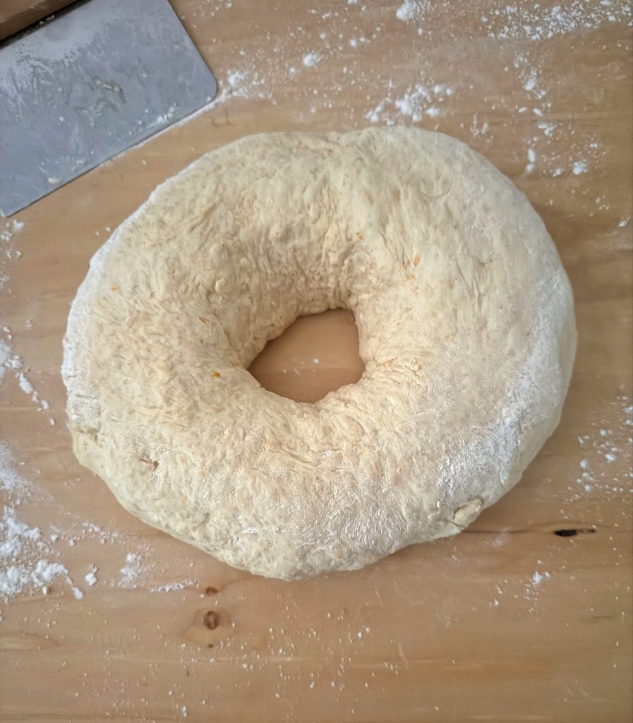 Dough shaped into a ring with a hole in the center on a floured board.