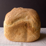 Baked loaf of Sourdough Bread Machine Bread resting on a white cloth