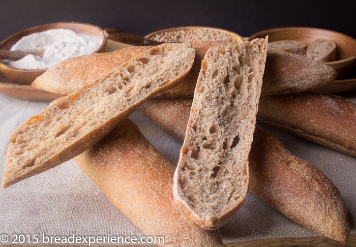 Crumb shot of Whole Grain Poolish Baguettes with milled flour in background
